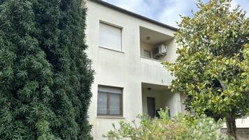 A two-story building with a balcony, a window, and an air conditioning unit.