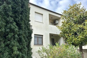 Un edificio de dos pisos con balcón, ventana y unidad de aire acondicionado.
