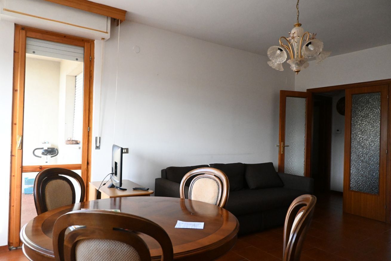Ein Essbereich mit rundem Tisch, Stühlen, einer Couch und einer Kristallleuchter.