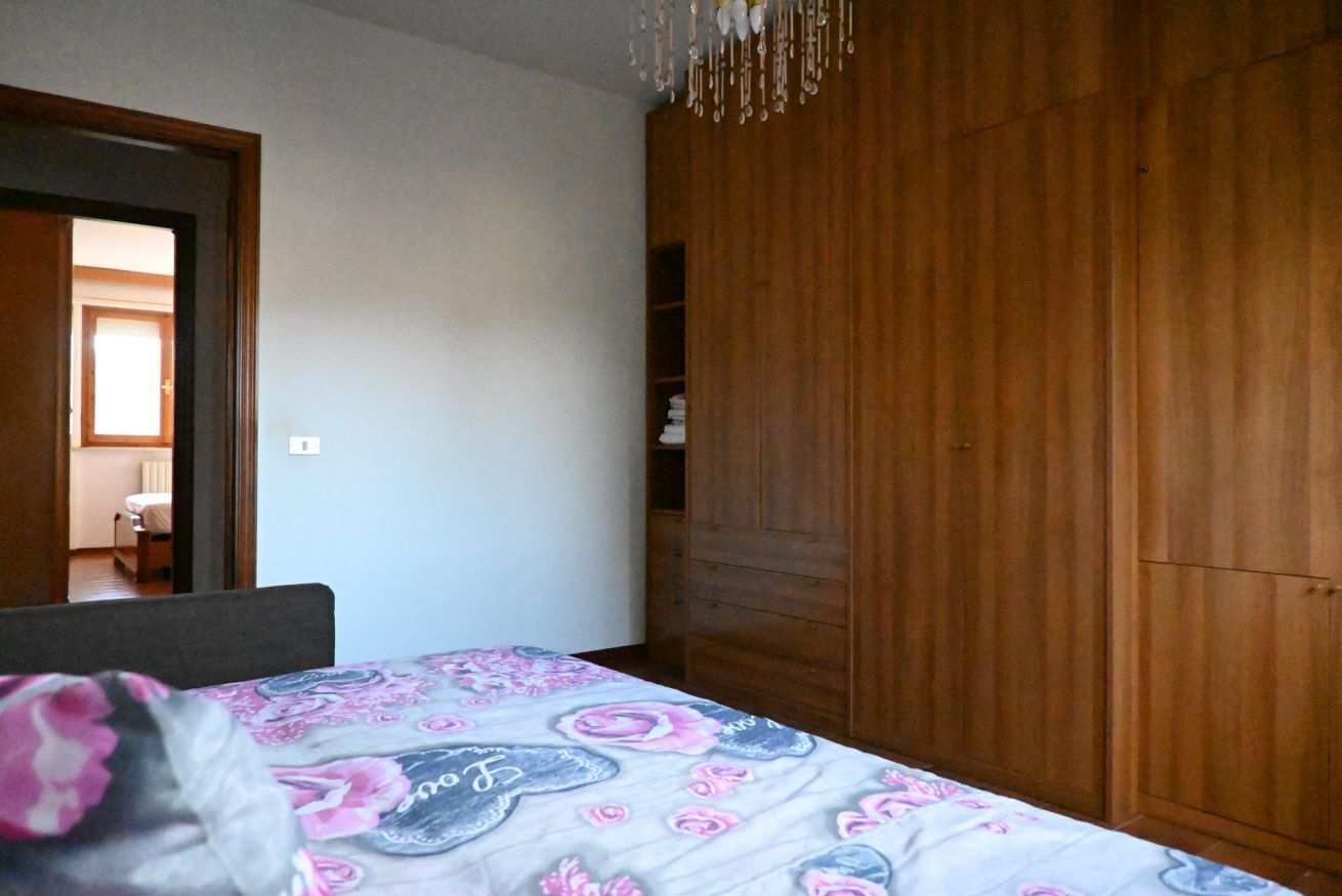 Ein Schlafzimmer mit Bett, Holzschrank und einer Chandel.