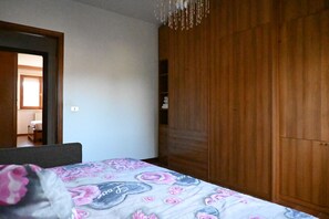 Un dormitorio con cama, armario de madera y candelabro.
