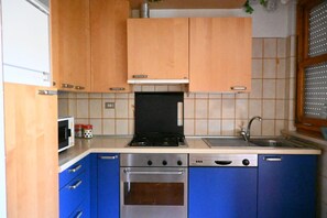 Una cocina con armarios de madera, estufa, microondas y lavavajillas.