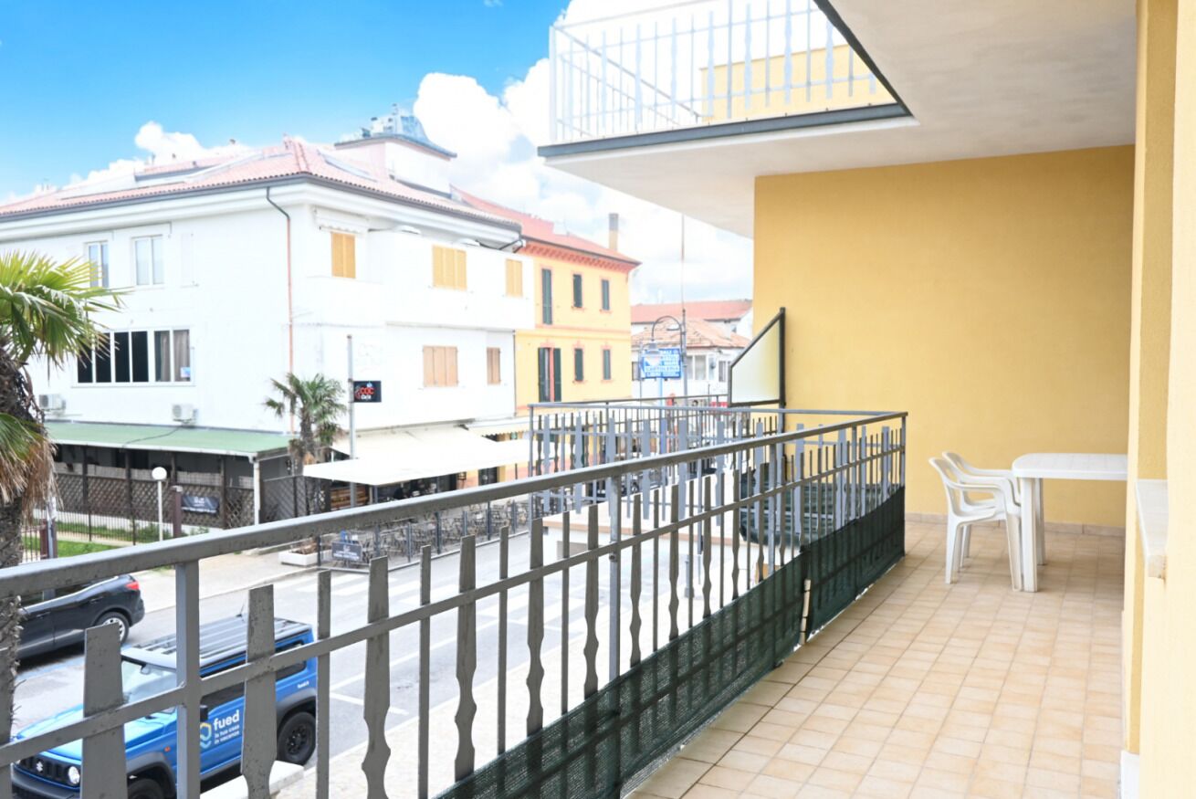 Un balcone con ringhiera, un tavolo bianco e sedie.