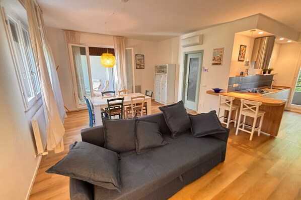 Una sala de estar moderna con sofá, mesa de comedor, sillas y una zona de cocina.