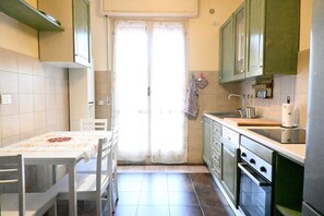 Une cuisine équipée d’une table à manger, de chaises, de placards, d’un évier et d’un four.