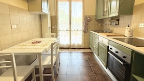 A kitchen with a table, chairs, a sink, cabinets, and an oven. - SE154 – Senigallia, large four-room apartment convenient to services (Senigallia)