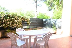 An outdoor patio with a round table and four chairs, surrounded by greenery and a covered area. - SE154 – Senigallia, large four-room apartment convenient to services (Senigallia)