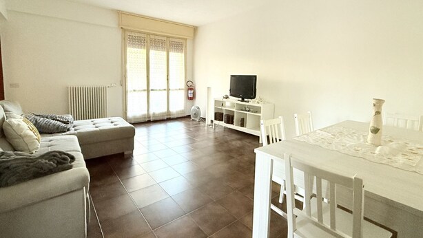 A living room with a sofa, a dining table, and a television. - SE154 – Senigallia, large four-room apartment convenient to services (Senigallia)