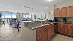 A modern kitchen with granite countertops, wooden cabinets, and a large island. - Perfect Getaway - Amazing Views Beach Front 2 Beds 2 Baths Hidden Dunes (Miramar Beach)