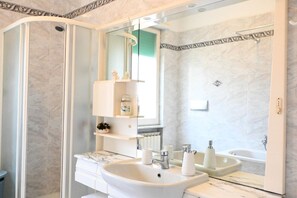 A bathroom with a glass shower enclosure, a white sink with a marble countertop, and a large mirror. - SE144 – Senigallia, comfortable three-room apartment with air conditioning (Senigallia)