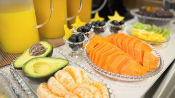 Un bufé con diversos alimentos, entre ellos frutas cortadas, queso y galletas.