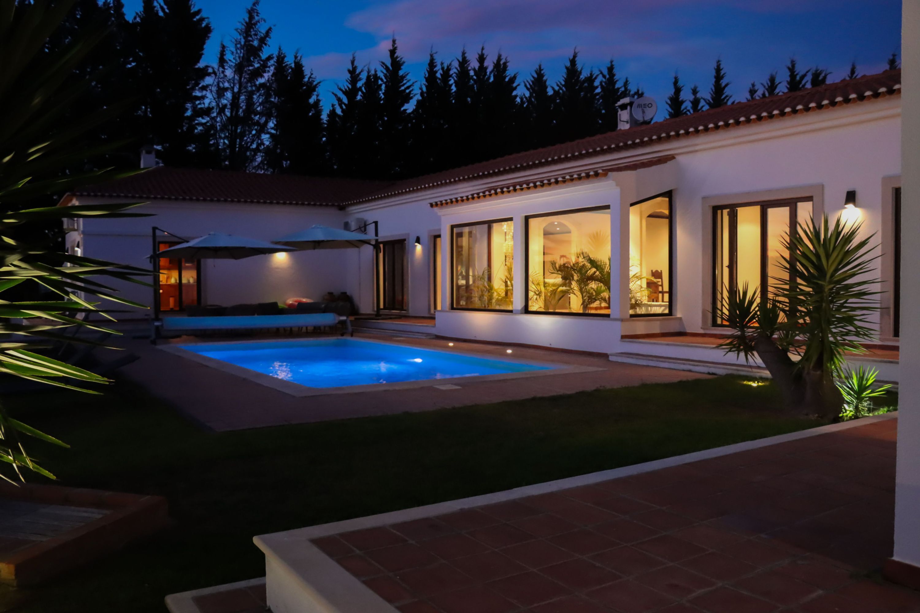 Una casa moderna con piscina, ventanas amplias y un patio bien iluminado.