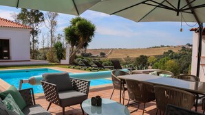 Un área junto a la piscina con una mesa de vidrio, sillas y un sofá.