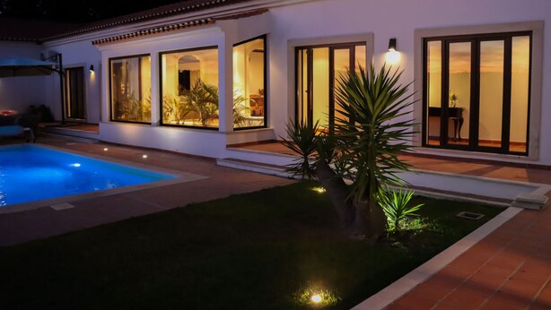 Una casa moderna con piscina, ventanas amplias y un patio bien iluminado.