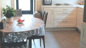 Eine kleine Küche mit weißen Schränken, einem Esstisch mit Spitze und einem Toaster.