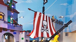 A play area with a pirate-themed backdrop, including a ship's wheel and a skull flag. - LEGOLAND California Hotel (Carlsbad)