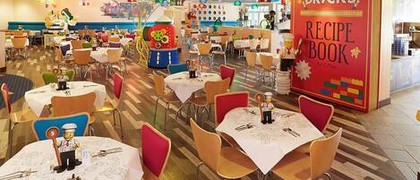 A restaurant interior with multiple tables, chairs, and a prominent red sign for a recipe book.