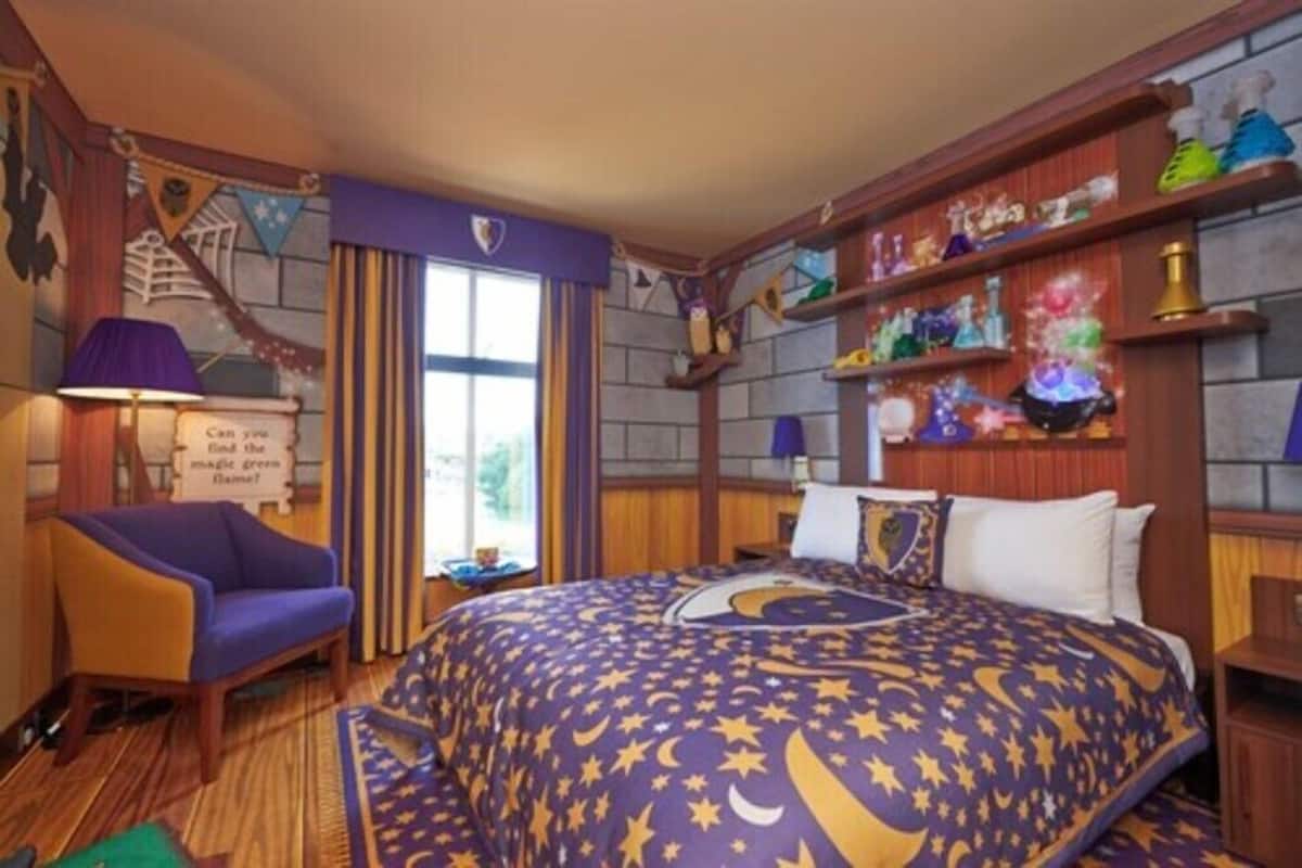 Una habitación de hotel temática con cama, una silla, escritorio y estantes con adornos.