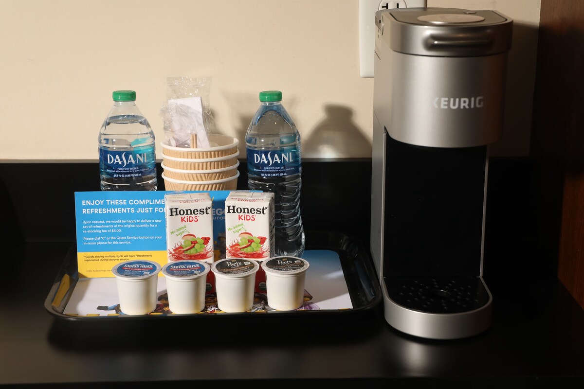 A tray with Dasani water bottles, Honest Kids juice cartons, and yogurt cups, along with a Keurig coffee maker.