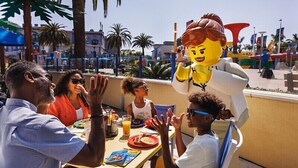 A group of people dining outdoors with a LEGO character mascot. - LEGOLAND California Hotel (Carlsbad)