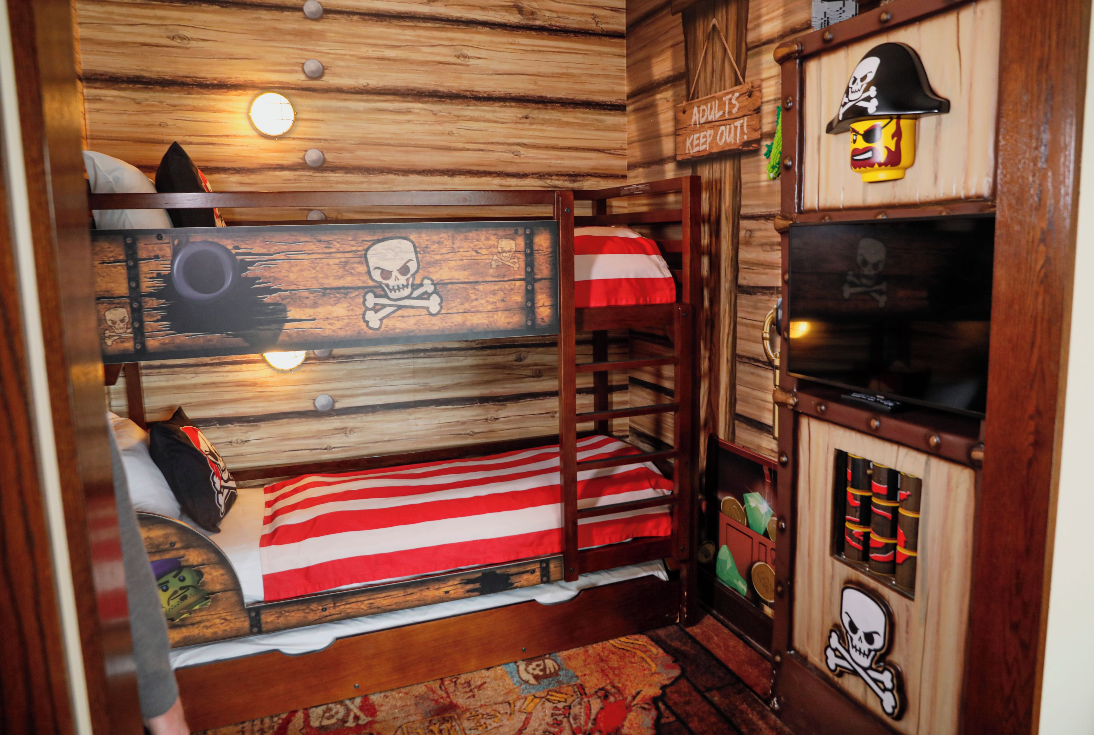 A bunk bed with a pirate-themed headboard and a small TV on a wooden cabinet.