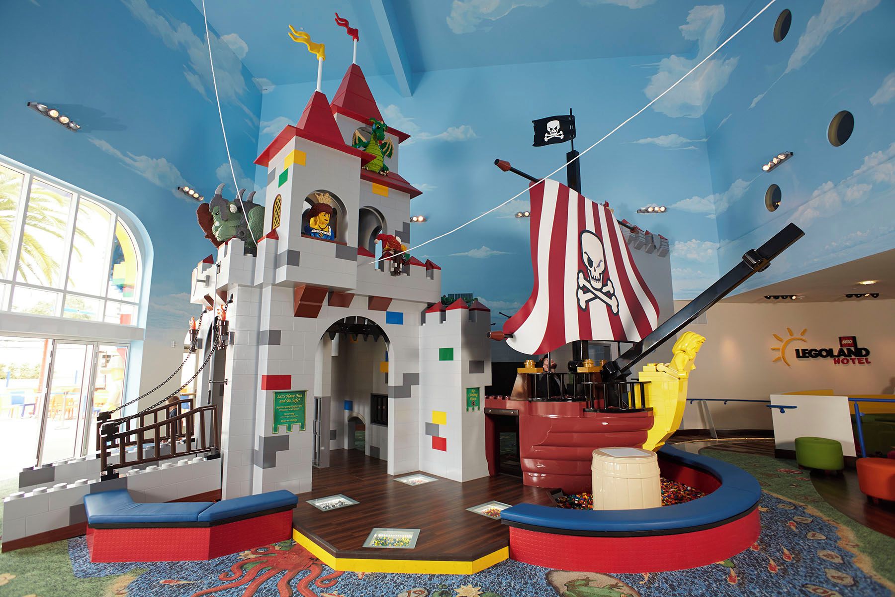 A LEGO play area with a pirate ship theme, including a castle and a ship with a skull and crossbones flag.