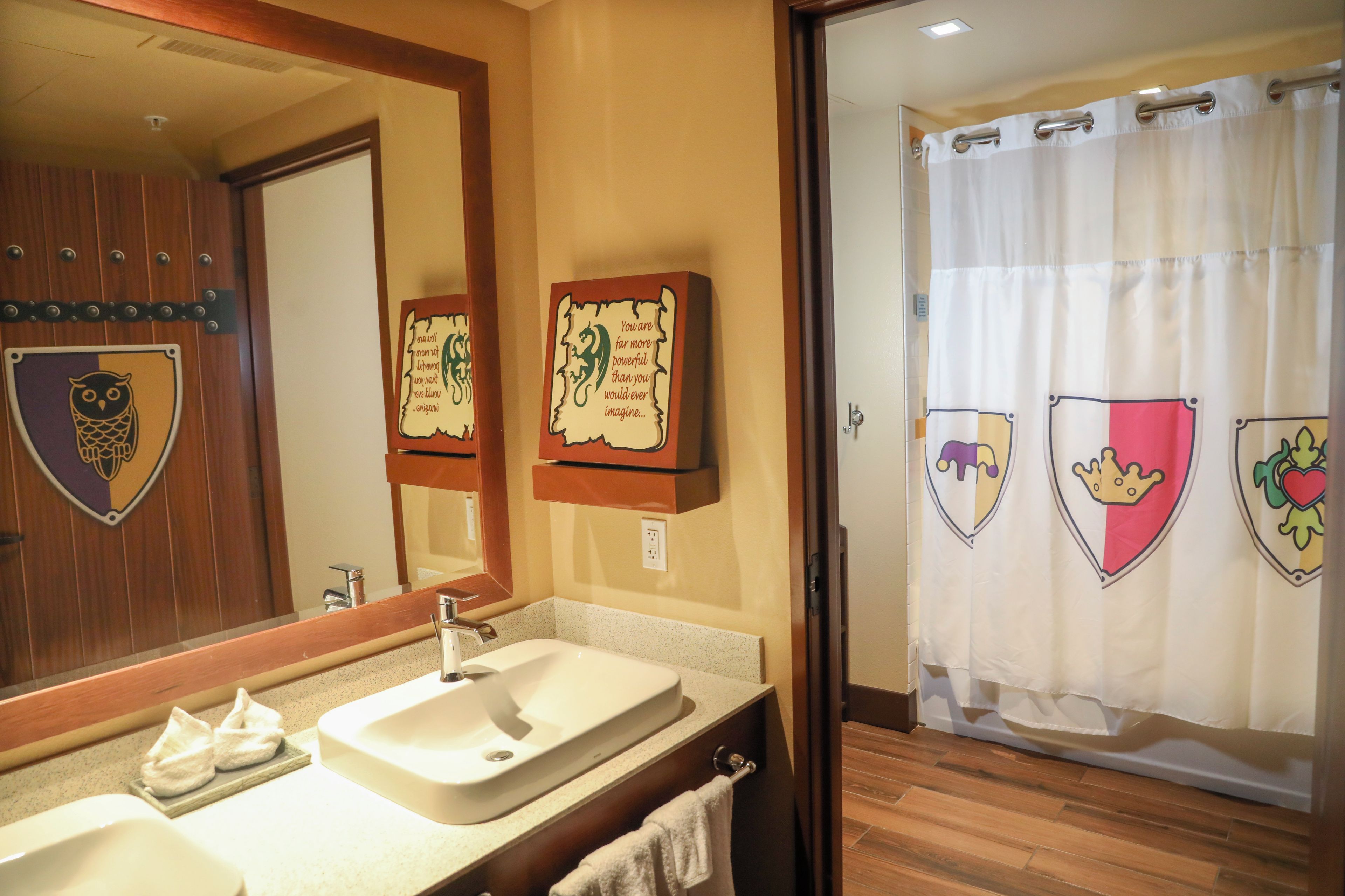 Un baño con lavamanos, espejo y dos frases motivacionales enmarcadas.