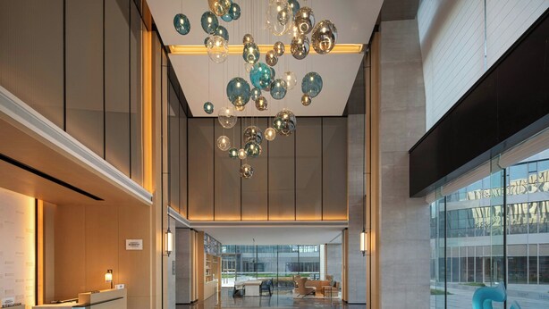 A modern lobby with a reception desk, seating area, and a unique ceiling installation.