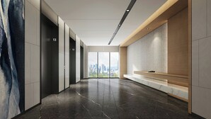 A modern hallway with a city view, featuring a bench, a phone, and a wall-mounted artwork.