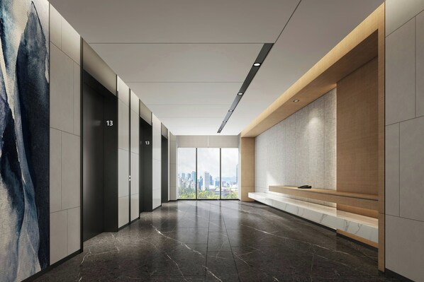 A modern hallway with a city view, featuring a bench, a phone, and a wall-mounted artwork.