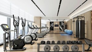 A modern gym with treadmills, elliptical machines, and weightlifting equipment.