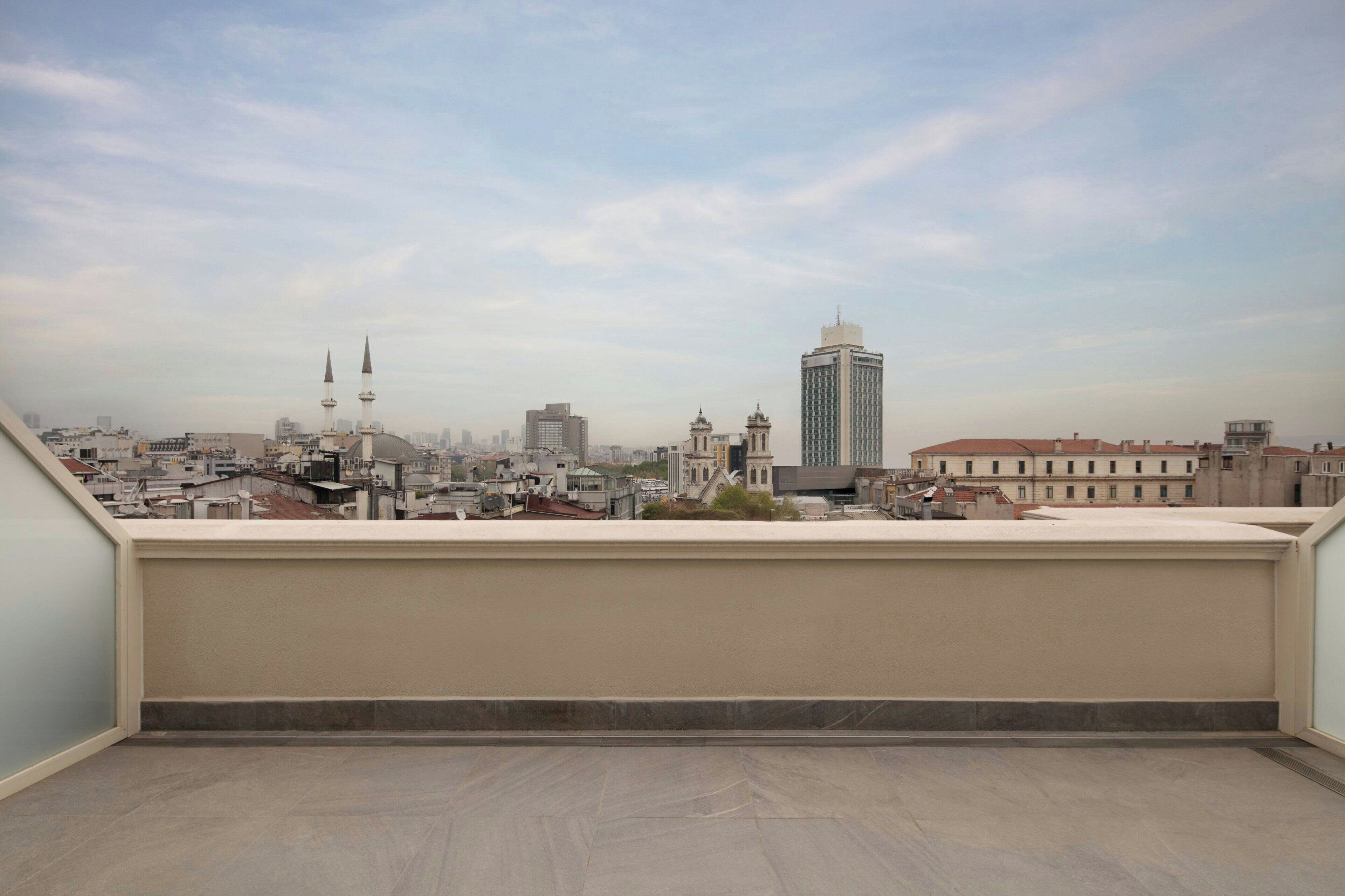 A rooftop terrace with a cityscape view, including a mosque and modern buildings.