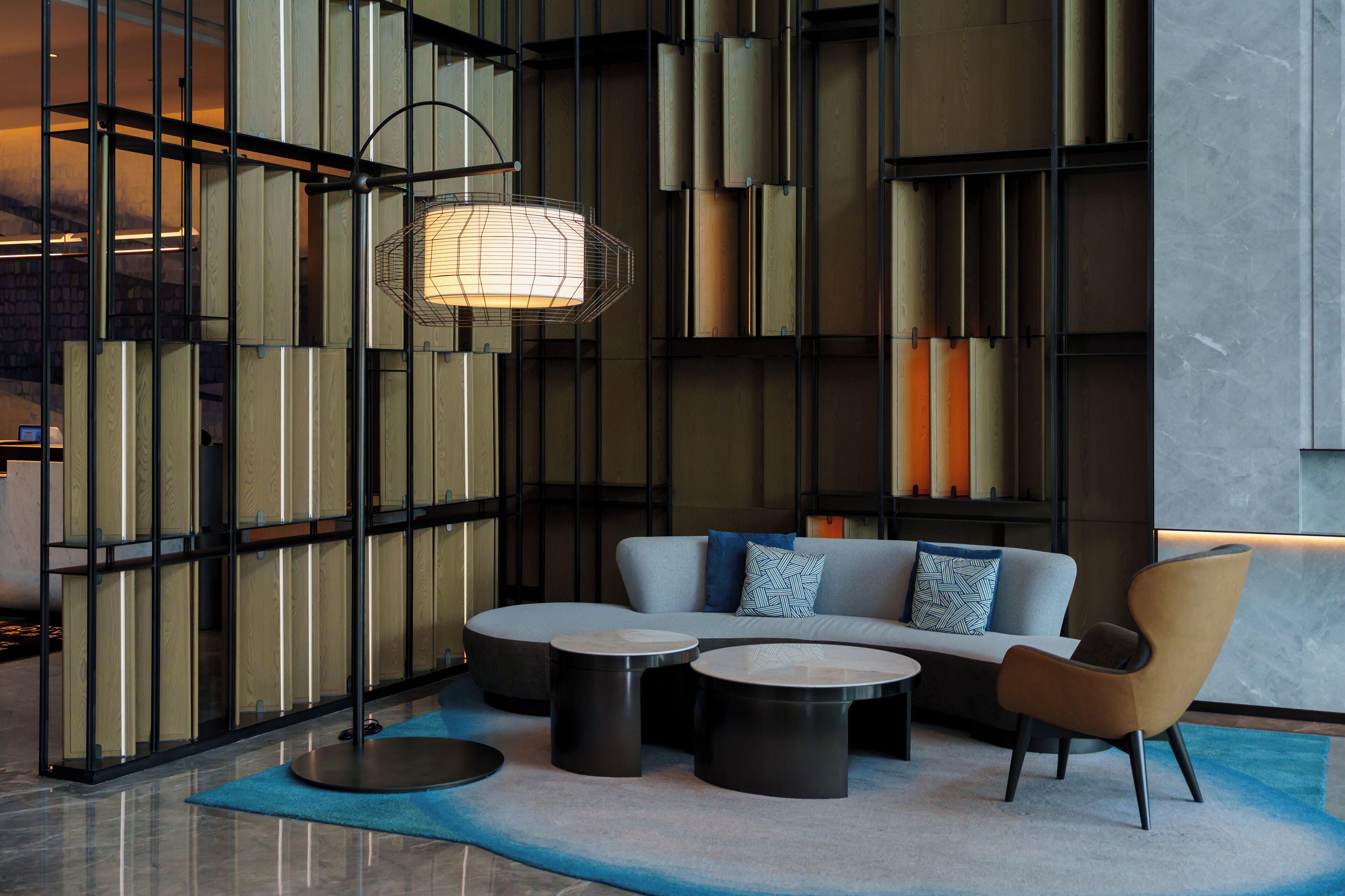 A modern lounge area with a sofa, two round tables, and a floor lamp.