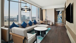 A modern hotel room with a large sofa set, a round coffee table, and a flat-screen TV mounted on the wall. - Courtyard By Marriott Nantong (Nantong)