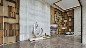 A modern lobby with a marble floor, a large abstract sculpture, and a seating area with a sofa and chairs. - Courtyard By Marriott Nantong (Nantong)
