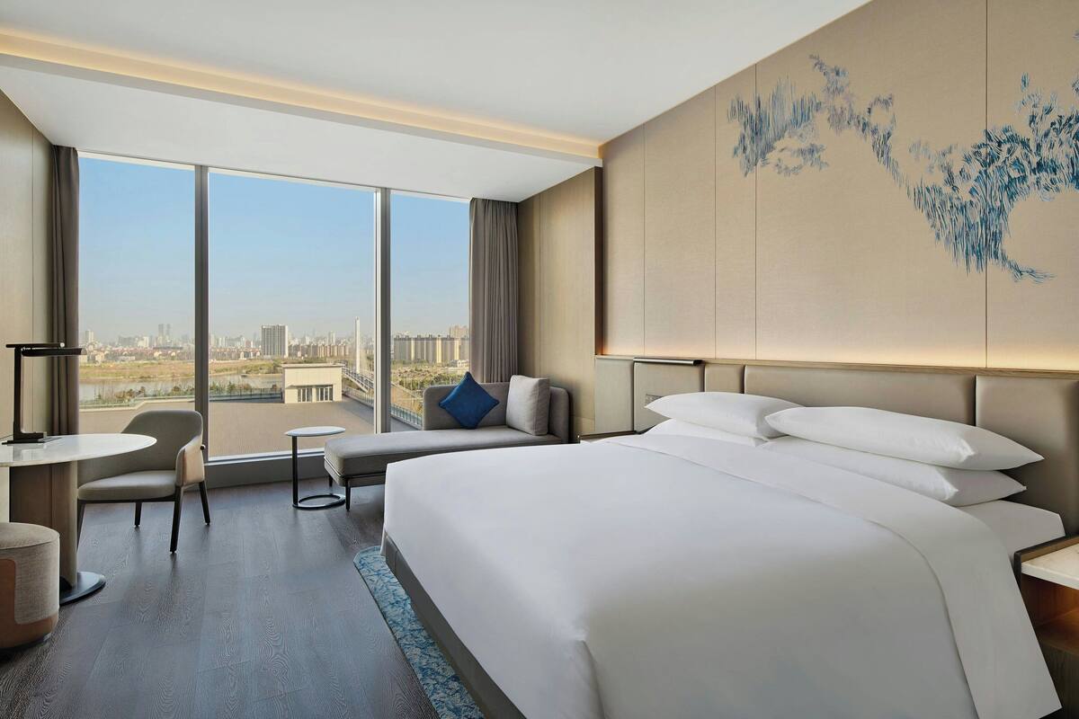 Une chambre d’hôtel moderne dotée d’un grand lit, d’un coin salon avec vue et d’un bureau.