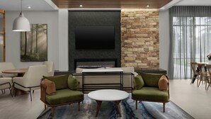 A modern living room with a fireplace, a flat-screen TV, and a stone accent wall. - Fairfield By Marriott Inn & Suites Weldon (Weldon)