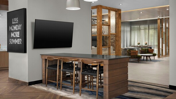 A modern bar area with a black TV, wooden stools, and pendant lighting. - Fairfield By Marriott Inn & Suites Weldon (Weldon)