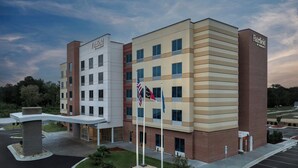 A multi-story Fairfield by Marriott hotel with a modern design, featuring a brick facade, multiple windows, and a landscaped entrance area with a flagpole. - Fairfield By Marriott Inn & Suites Weldon (Weldon)