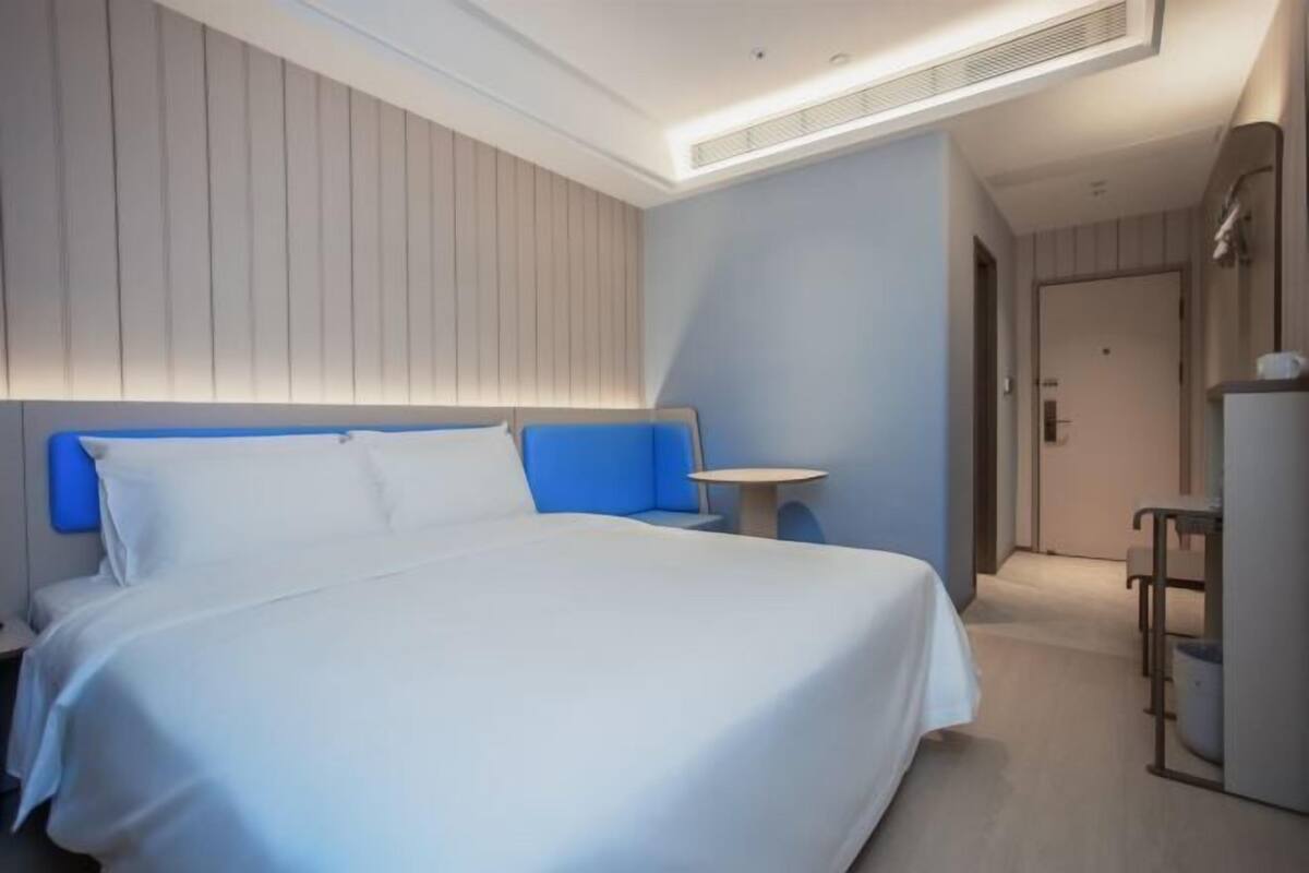 A modern hotel room with a large bed, a bedside table, and a small desk.