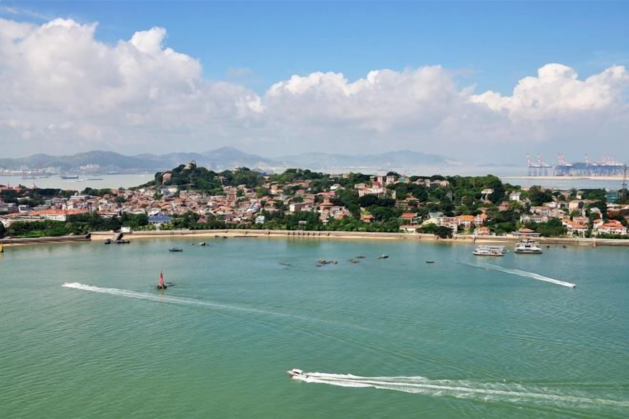 A coastal cityscape with a marina, boats, and a hilly backdrop.