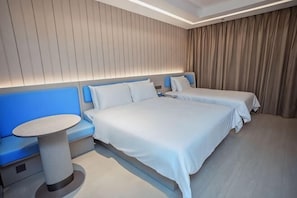 A hotel room with two beds, a round table, and a blue bench.