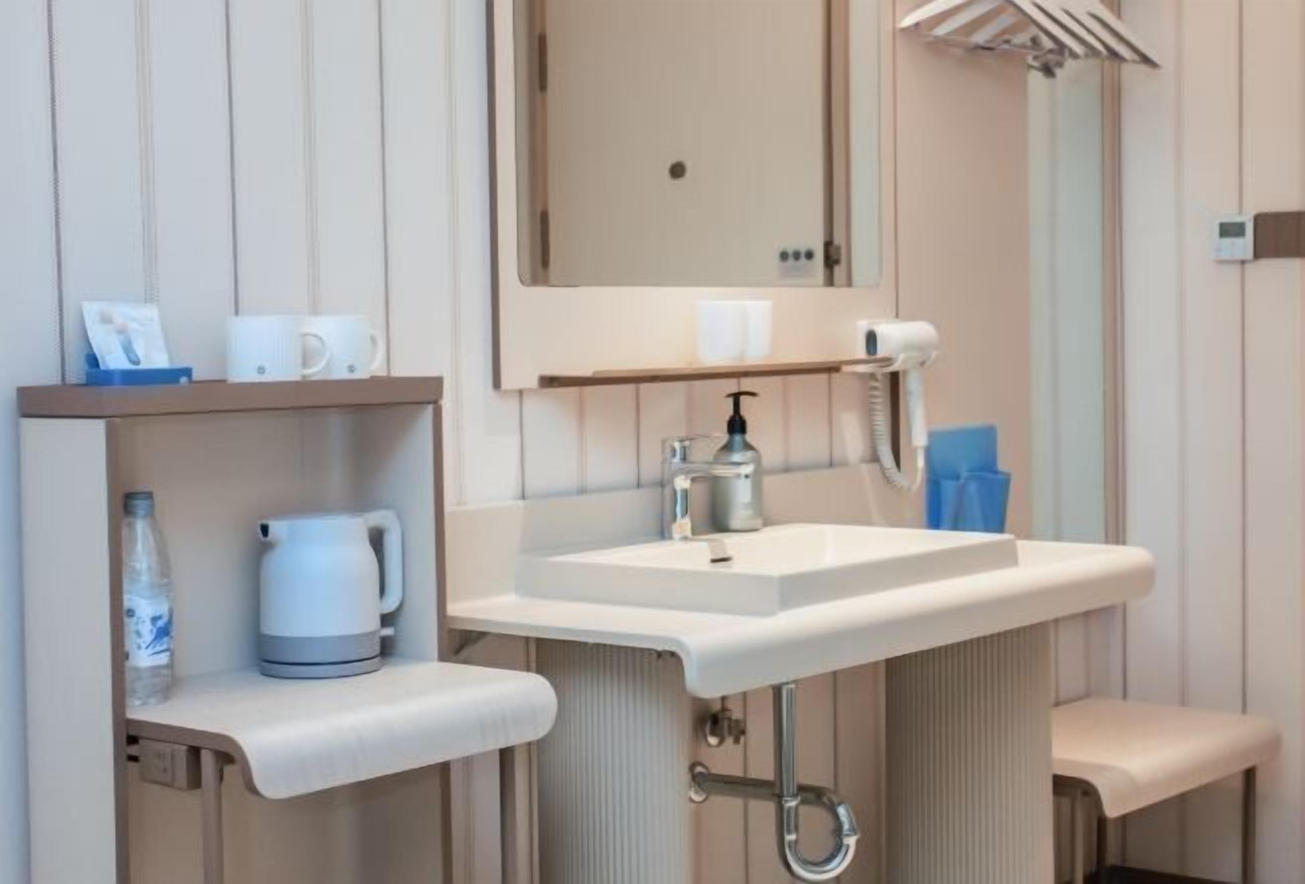 Une salle de bain moderne avec un lavabo, un miroir et un porte-serviettes.