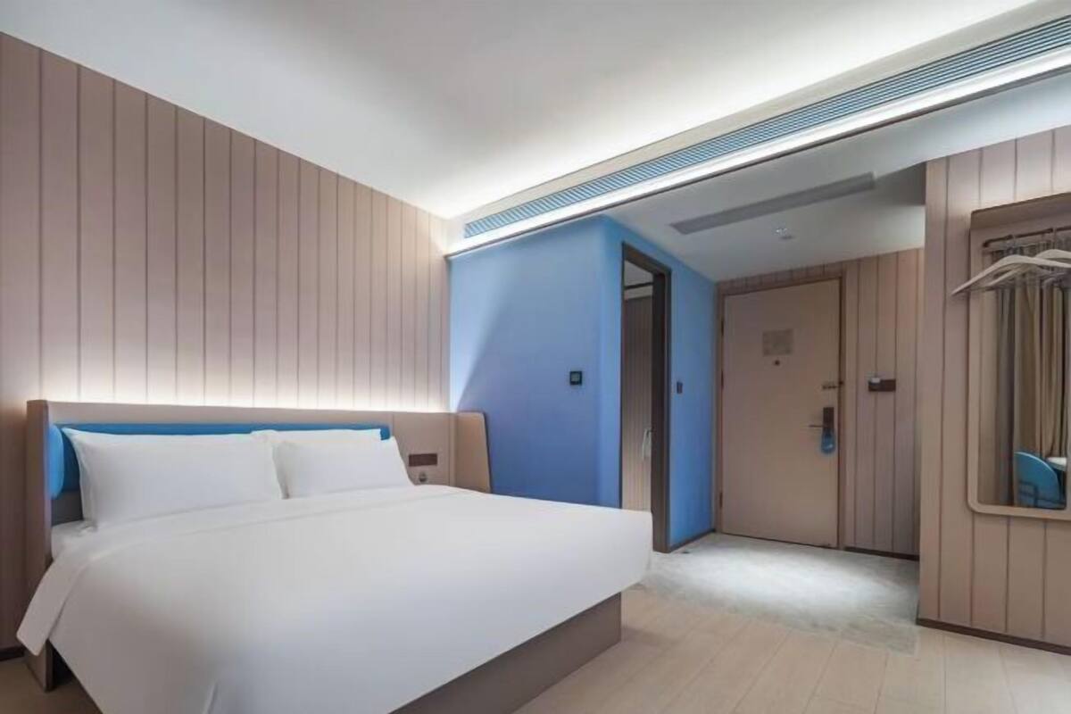 A hotel room with a large bed, a wardrobe, and a mirror.