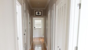 Un pasillo con piso de madera y puertas blancas.