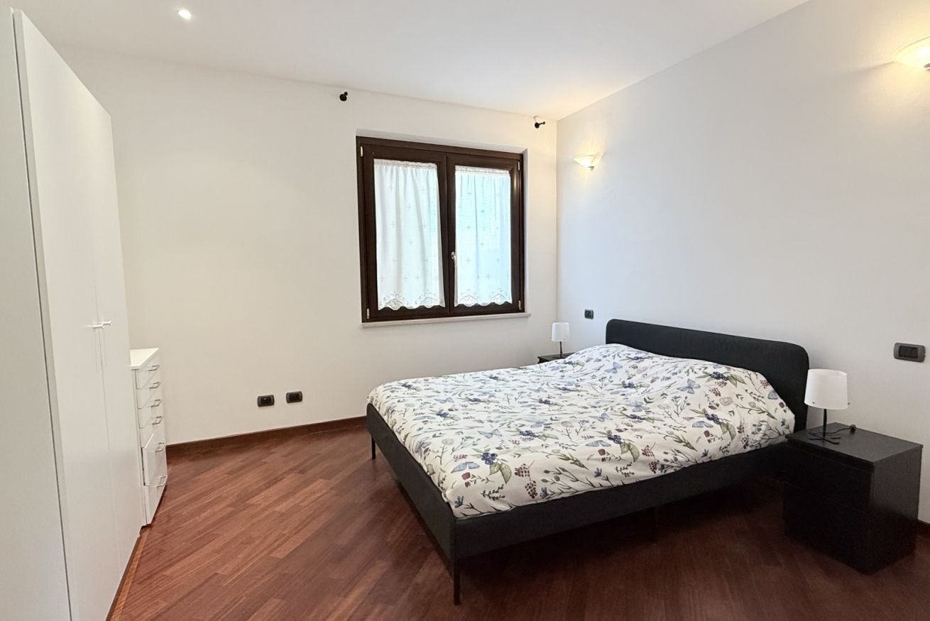 Ein Schlafzimmer mit einem Bett, einem Nachttisch, einem Kleiderschrank und einem Fenster mit Vorhängen.