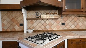 A kitchen with a gas stove, wooden cabinets, and a tiled backsplash.