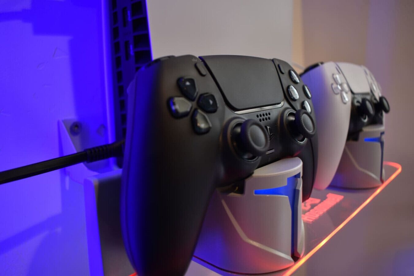 Twee gamecontrollers gemonteerd op een voetstuk, verlicht met blauw licht.