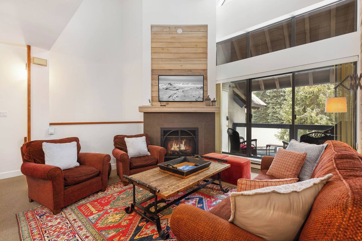 Una sala acogedora con chimenea, dos sillones, un sofá y una mesa de centro.