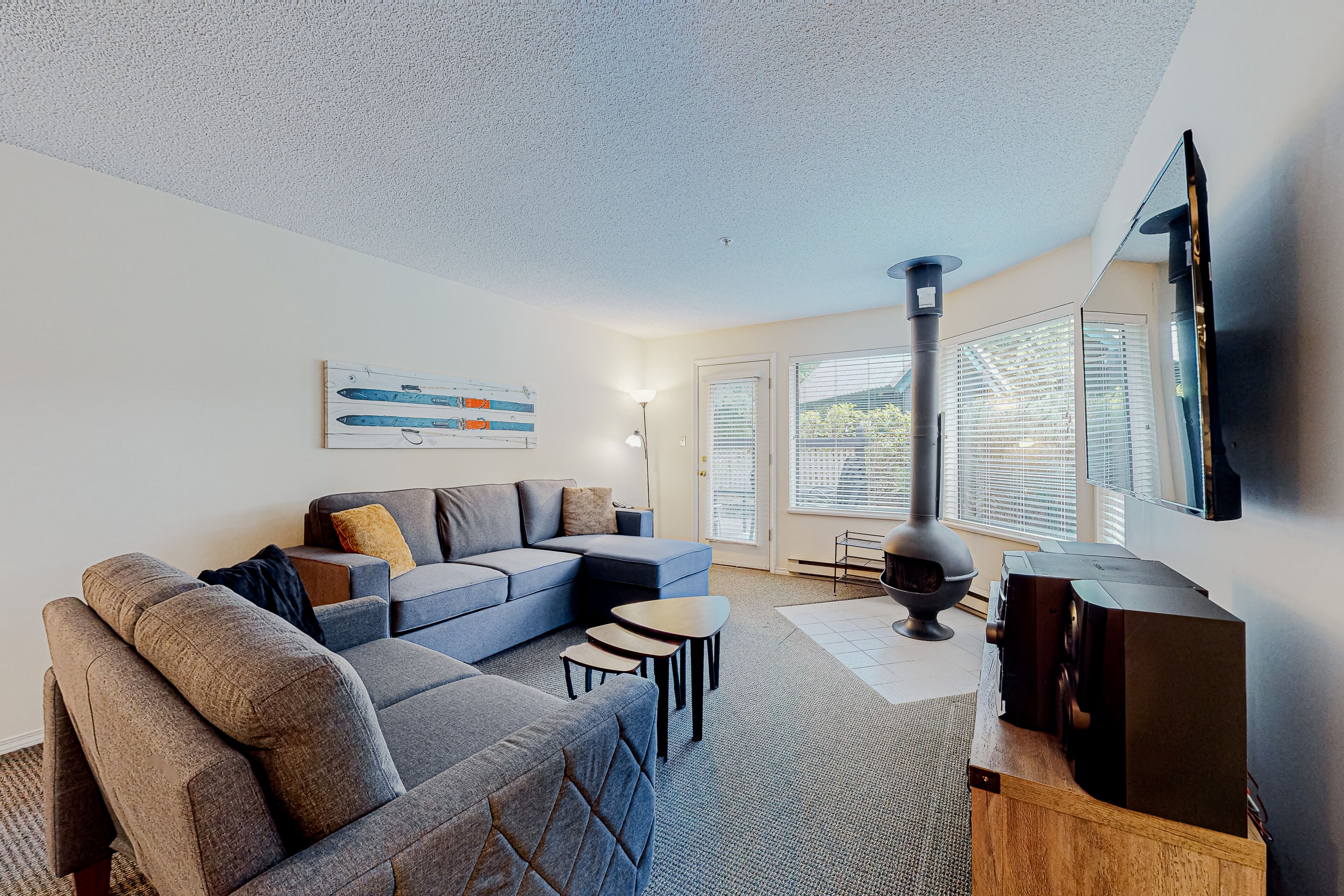 A modern living room with a sectional sofa, a flat-screen TV, and a fireplace.